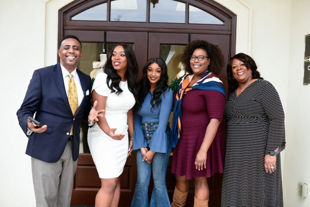 3 women and 2 men standing beside black wooden door